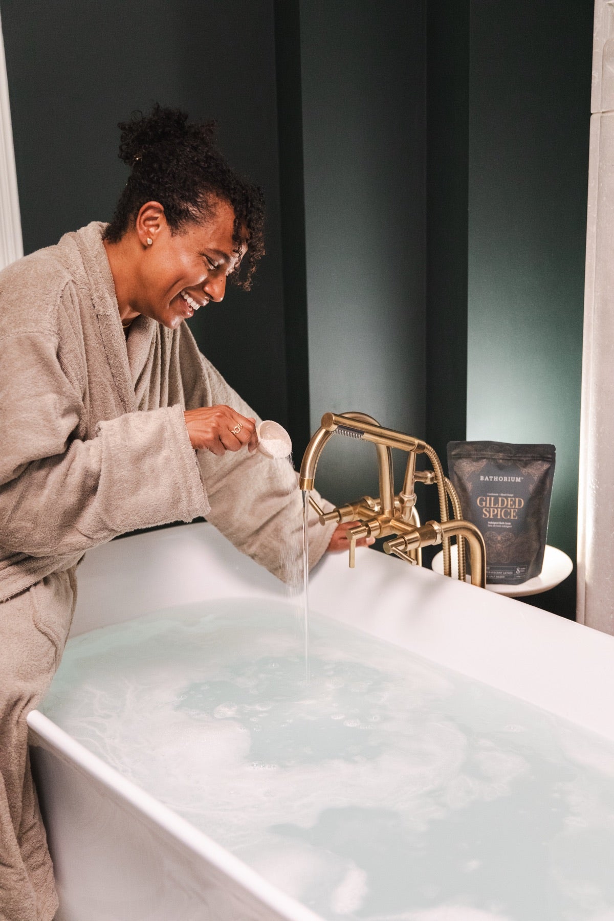 Pouring Gilded Spice into a running bath, the pouch on the tub edge