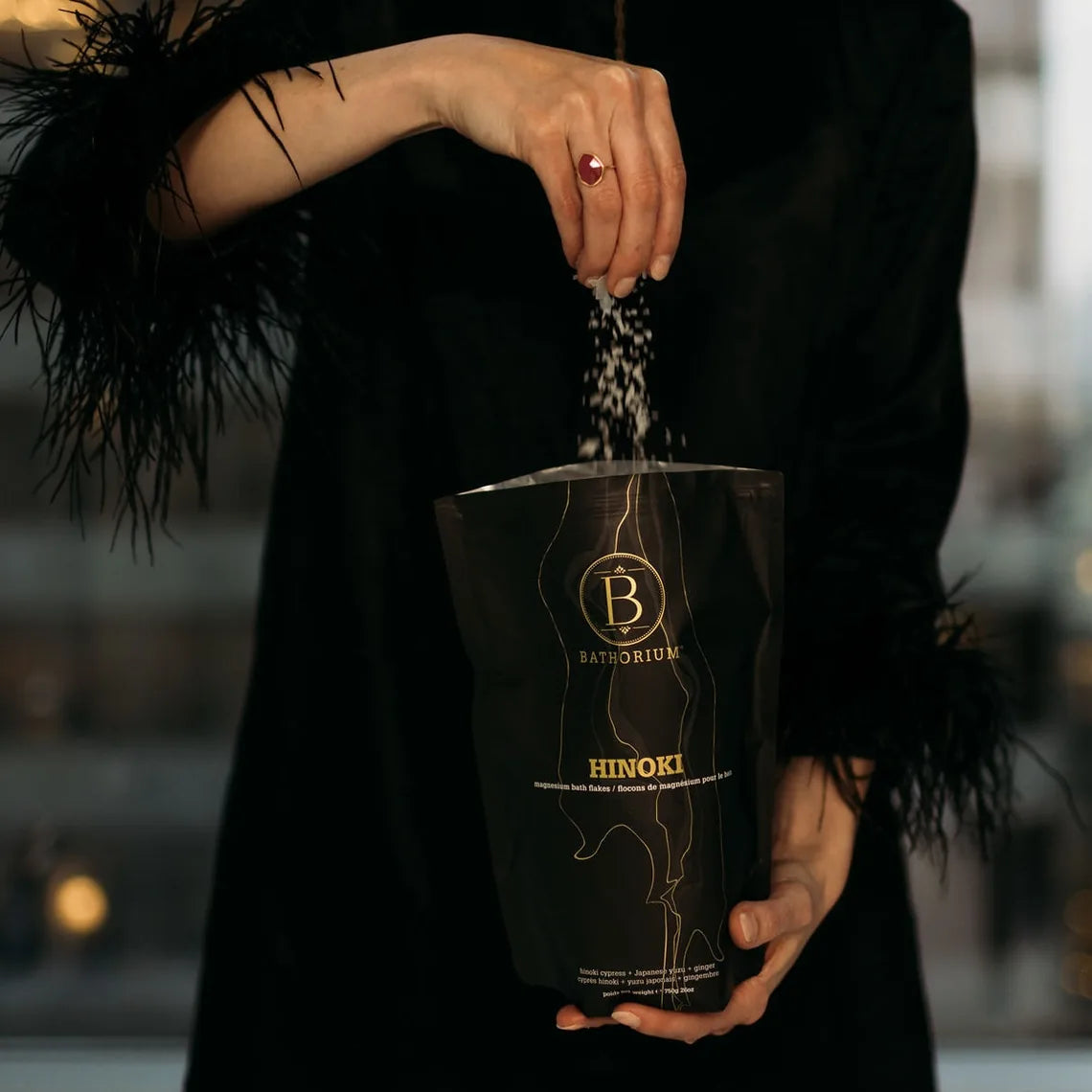 A woman holding a bag of Hinoki Magnesium Bath Flakes