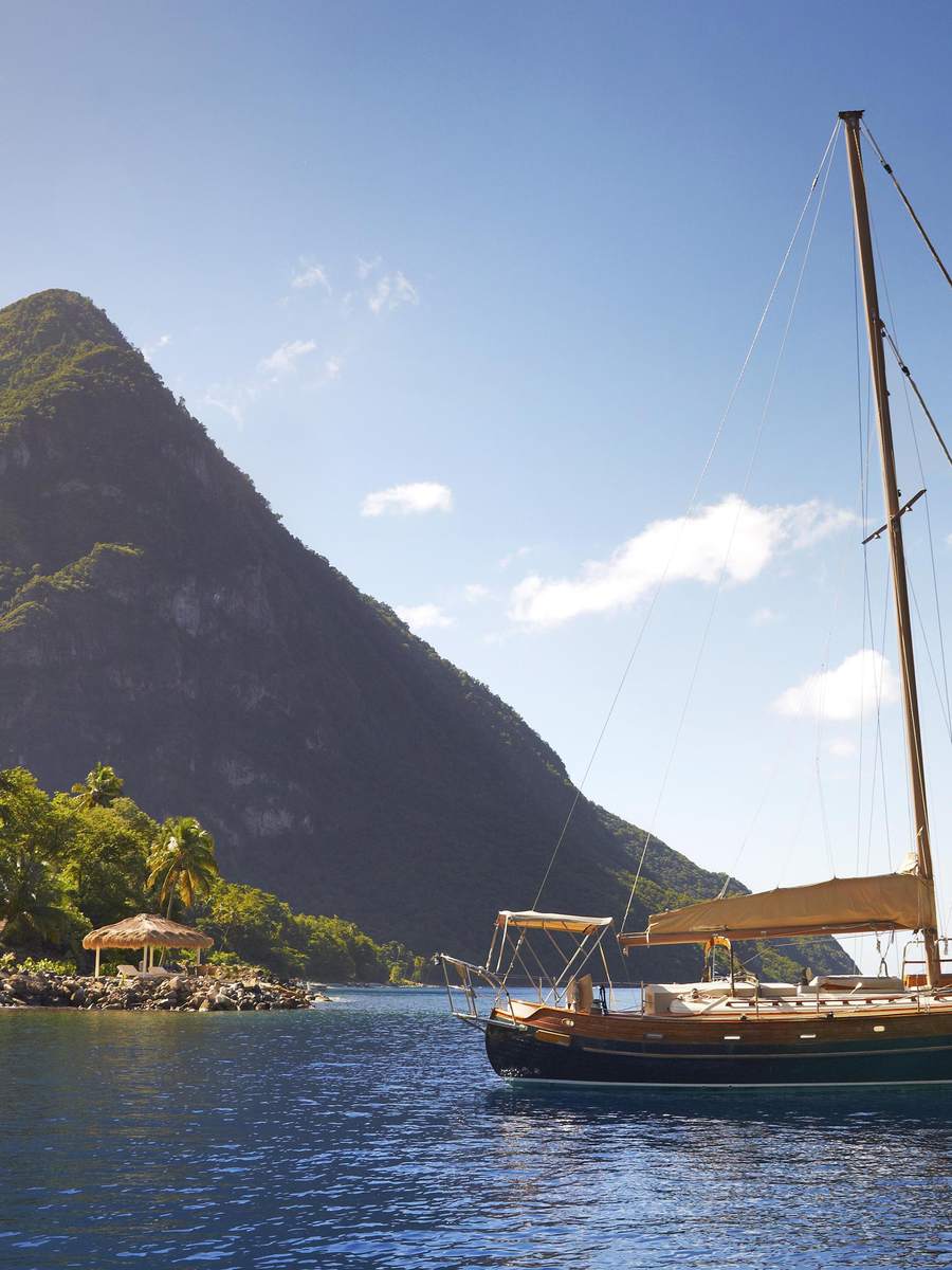 A sailboat anchored in the bay below a Piton at Sugar Beach